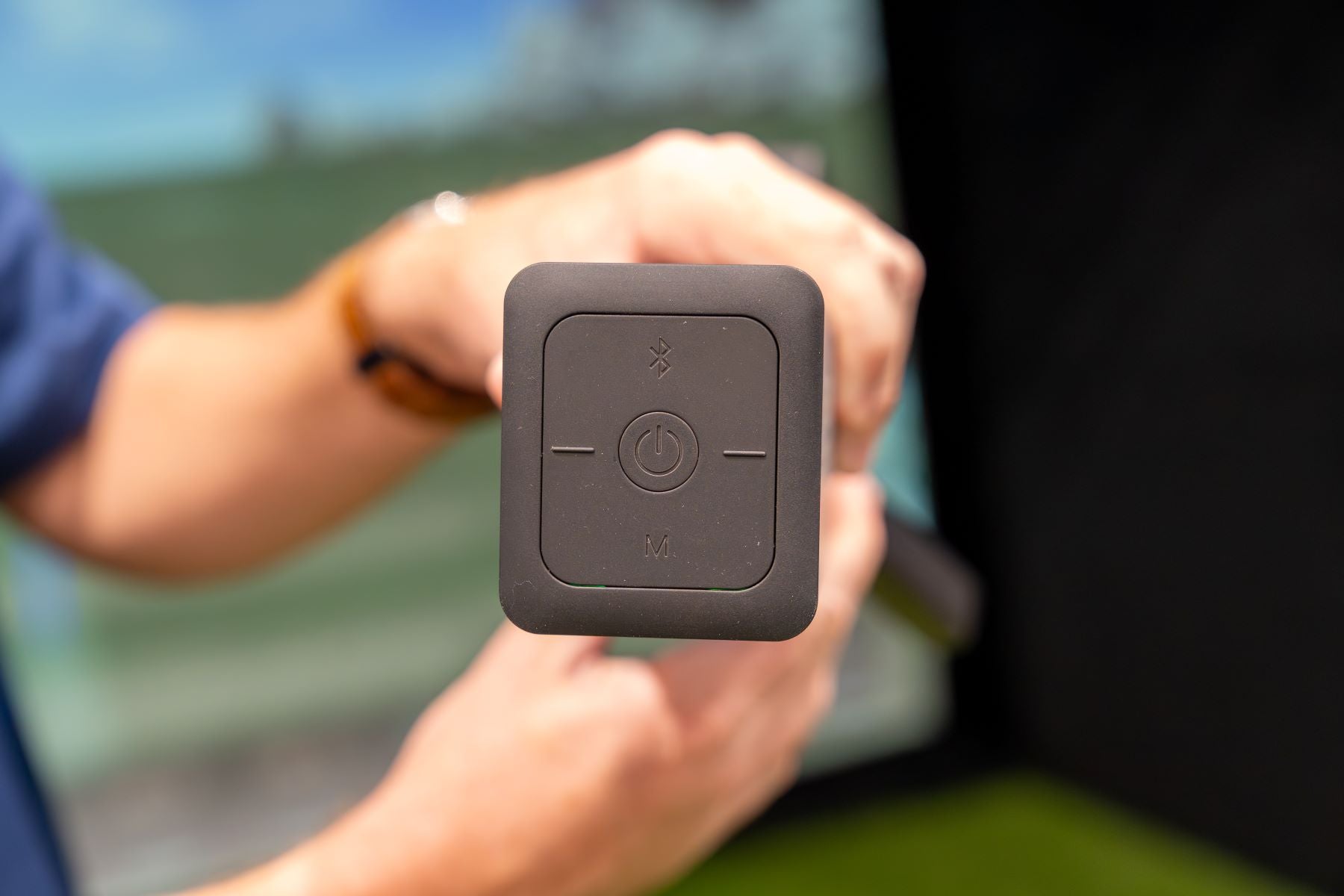 Hands holding the top control panel of the Square Golf Omni