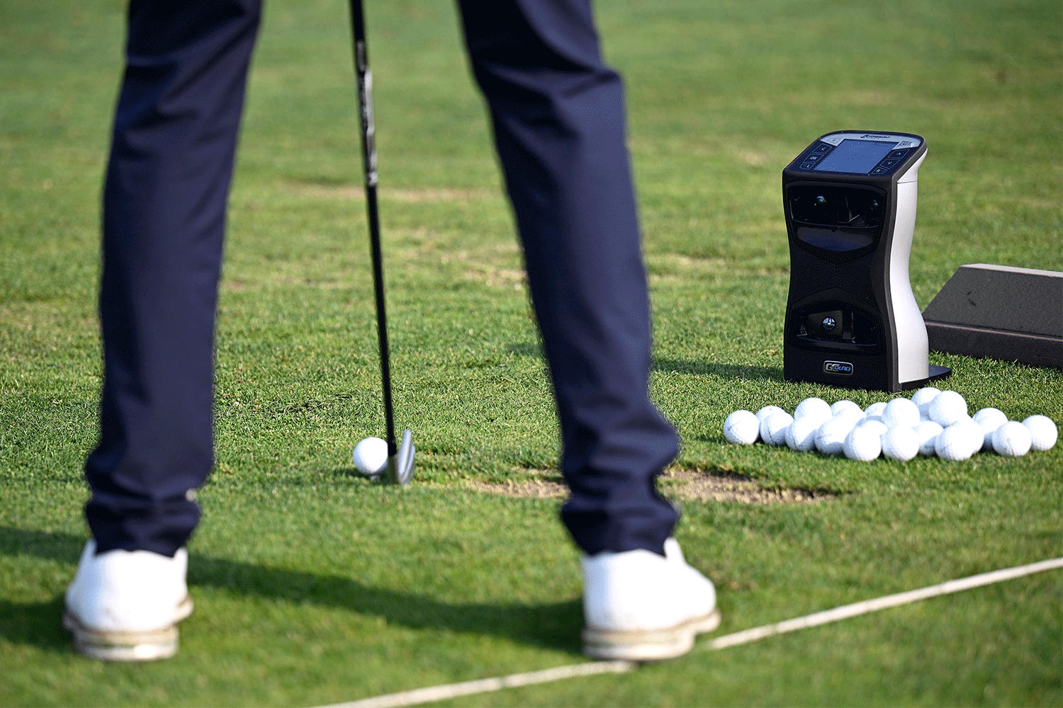 Real-use photo of a Foresight GCQuad launch monitor beside a golfer on a practice range