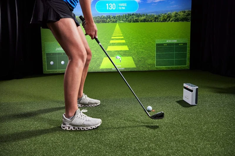 Official photo of a real woman using SkyTrak ST Plus in an indoor golf simulator