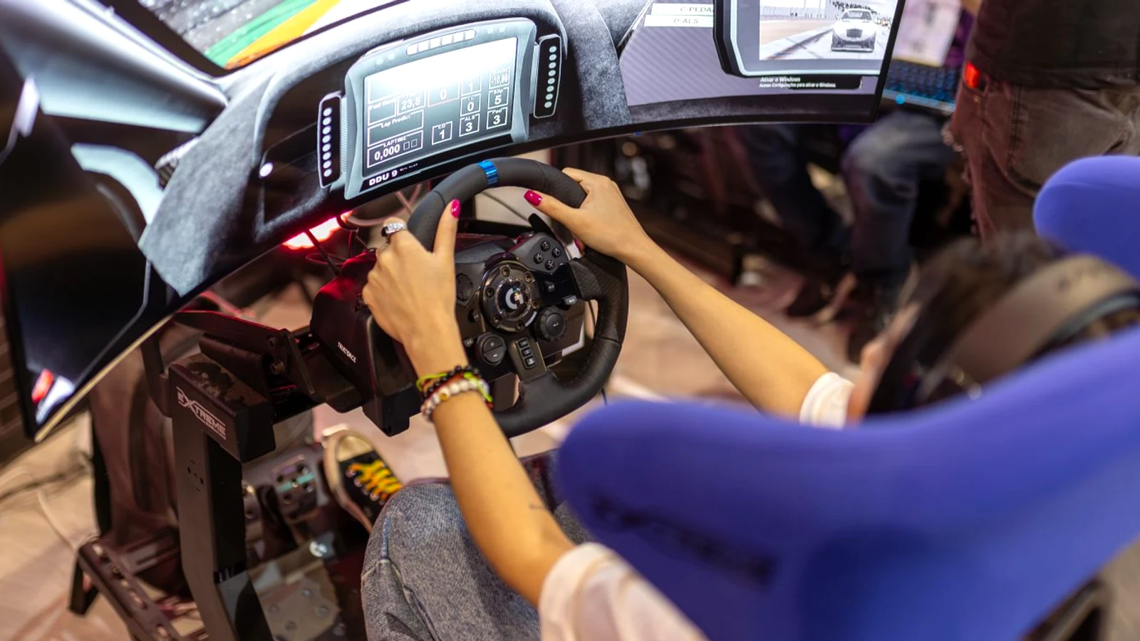 Real person driving a racing simulator at a gaming event with hands on a force feedback wheel